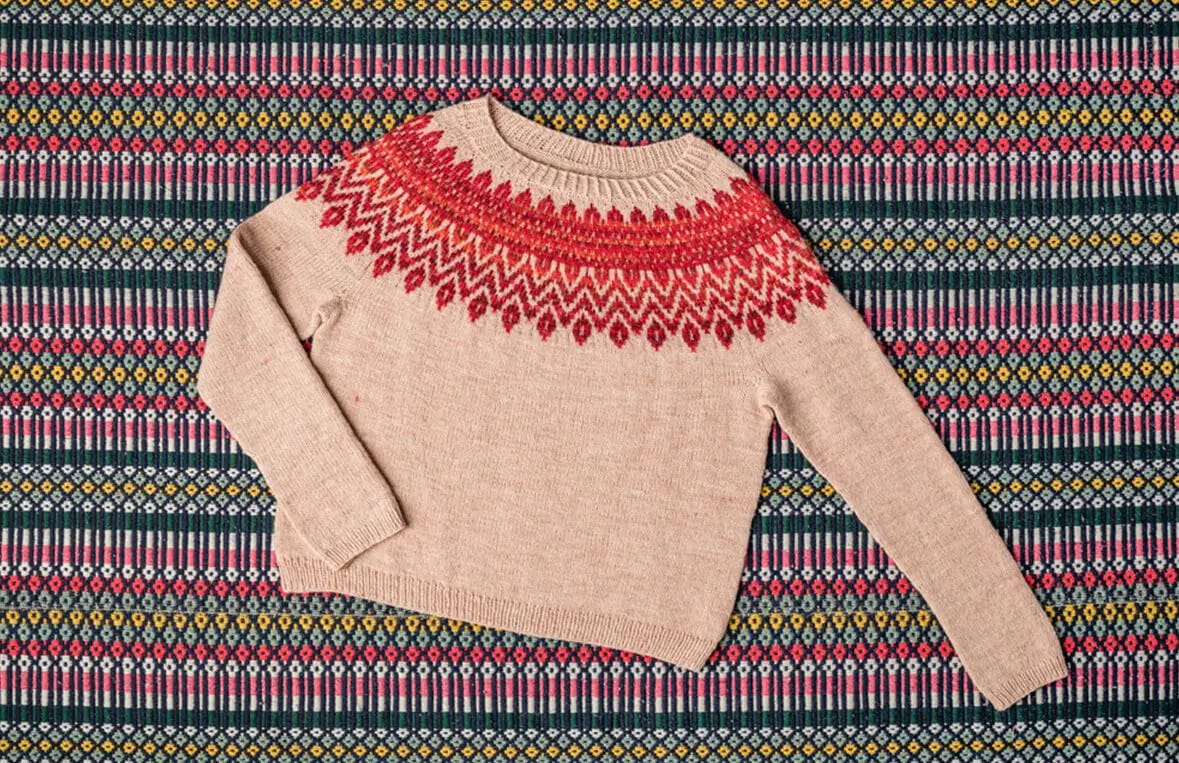 beige sweater with red colorwork yoke on an alentejano blanket