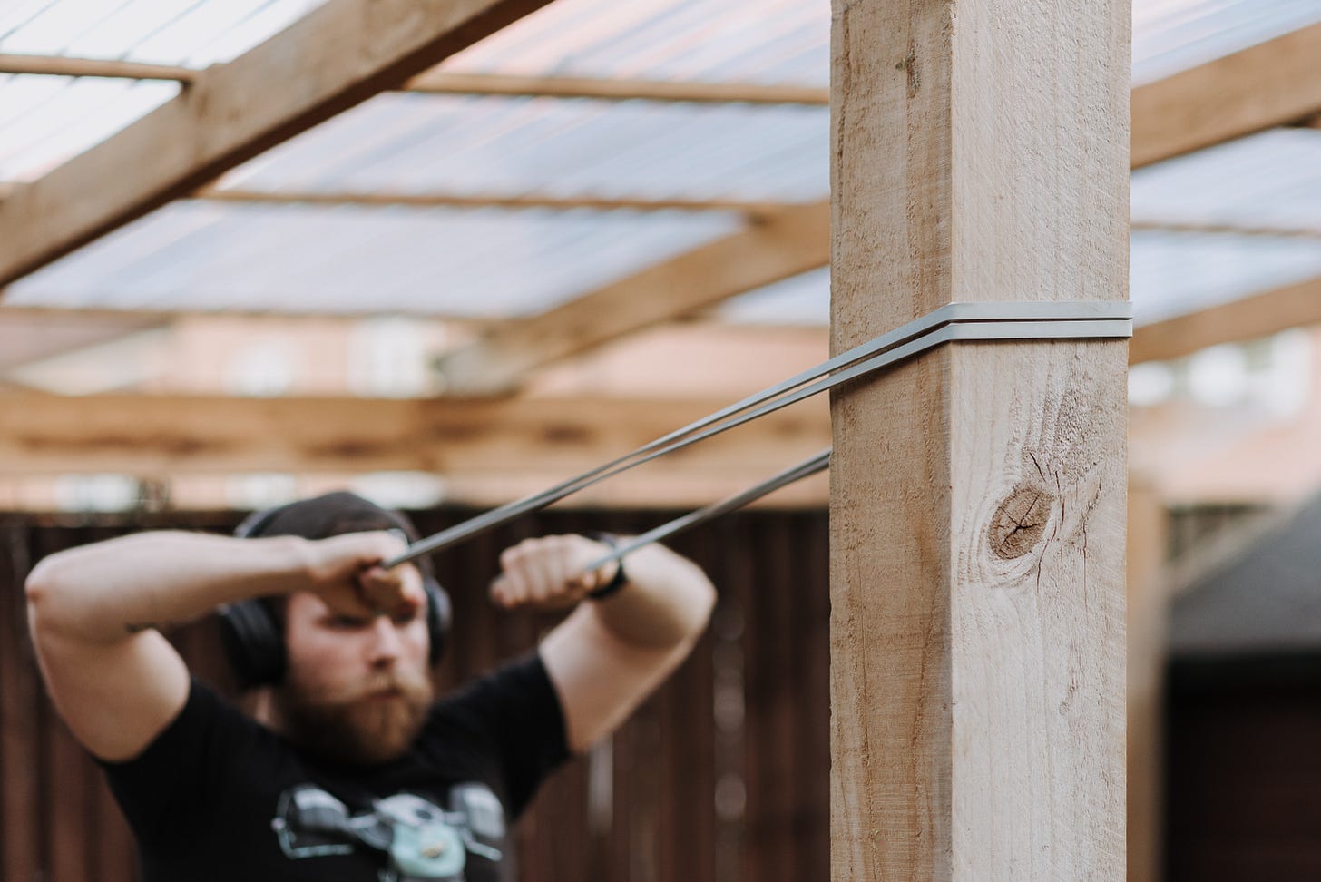 a man pulling on a band wrapped around a wooden pole a man pulling on a band wrapped around a wooden pole