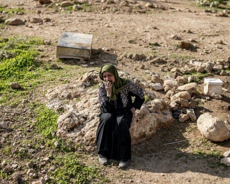 A woman sits alone, crying, in a rural setting