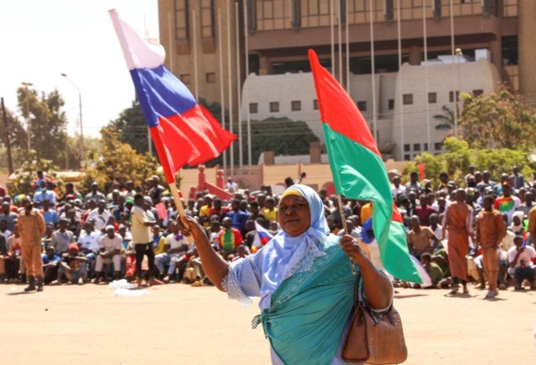A woman holds her national flag and the Russian flag as people gather to show their support for Burkina Faso's new military leader Ibrahim Traore. A woman holds her national flag and the Russian flag as people gather to show their support for Burkina Faso's new military leader Ibrahim Traore.