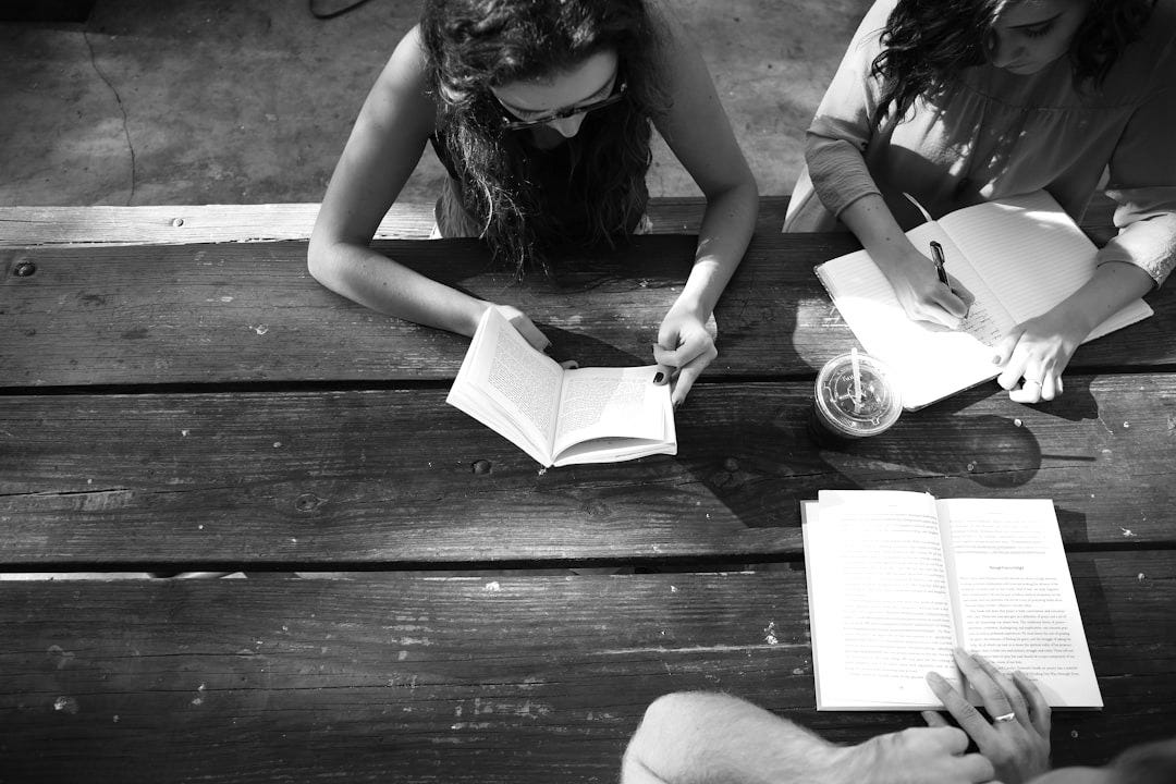 woman reading book while sitting on chair woman reading book while sitting on chair