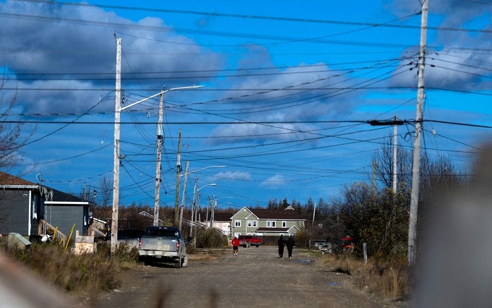 A photo shows the streets of a town with utility poles carrying many wires. 