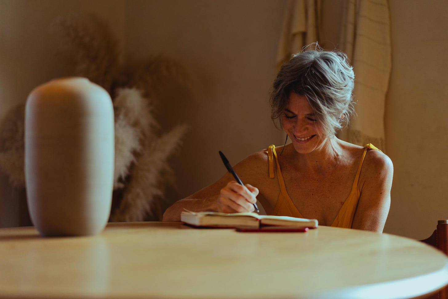 An older woman writing in her diary while smiling