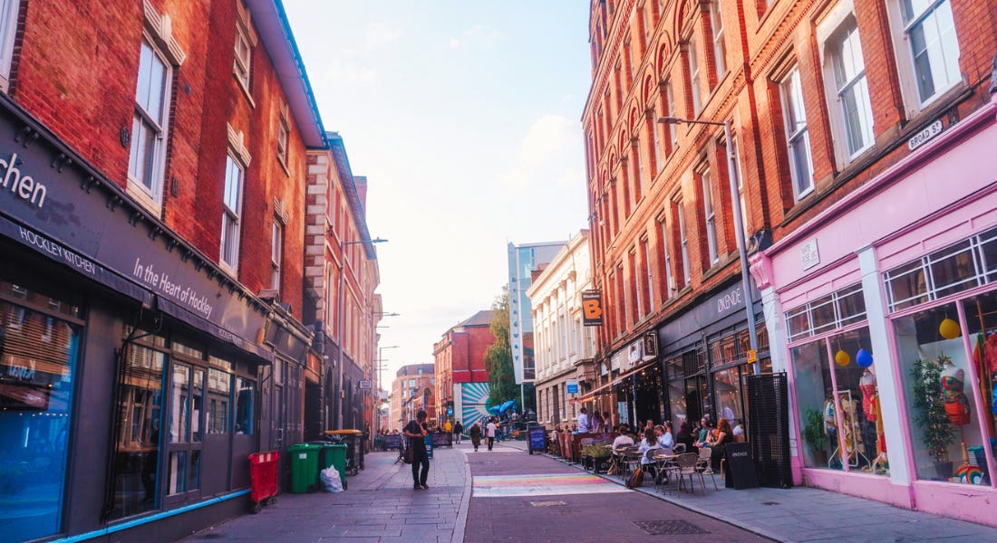 A street with brick buildings either side and a path with a rainbow pattern on it