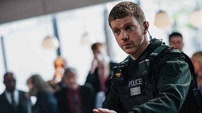 A police officer attempts to calm someone down - that someone is off screen.