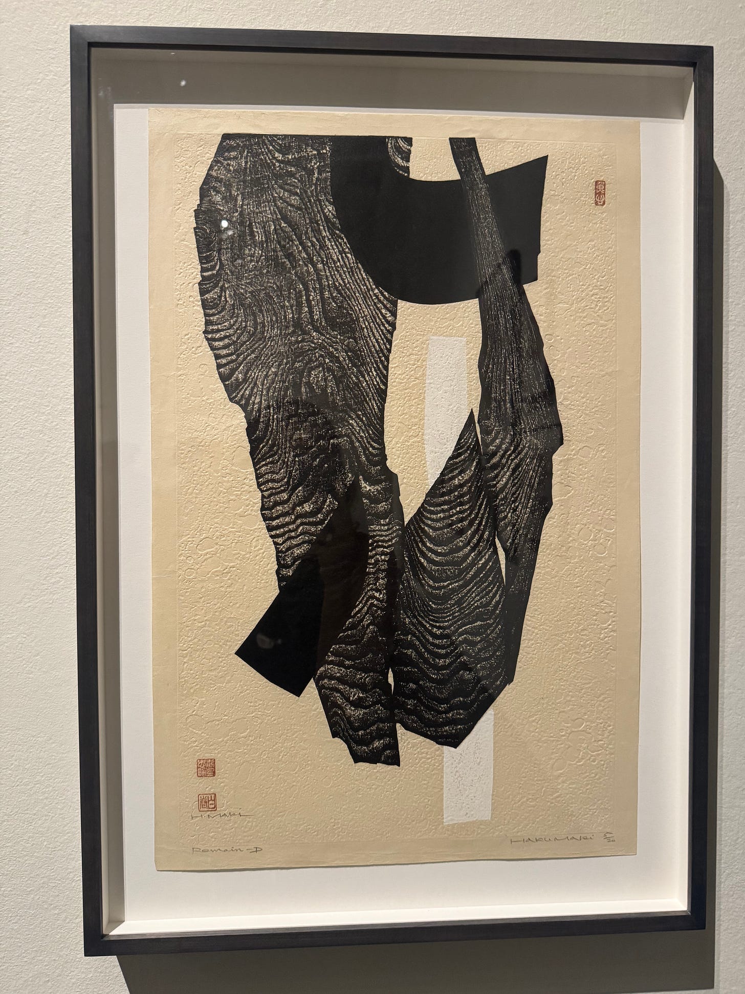An abstract black-and-white print by Haku Maki featuring layered, textured forms arranged vertically on handmade paper.