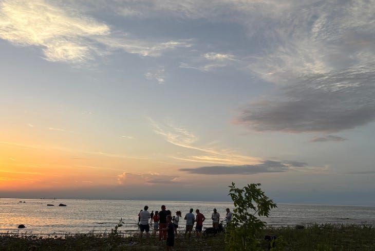 friends gathered along the shore at sunset friends gathered along the shore at sunset