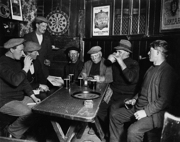 A group of men, one knitting, others raising glasses of beer, at the Jolly Sailor's Inn in ...