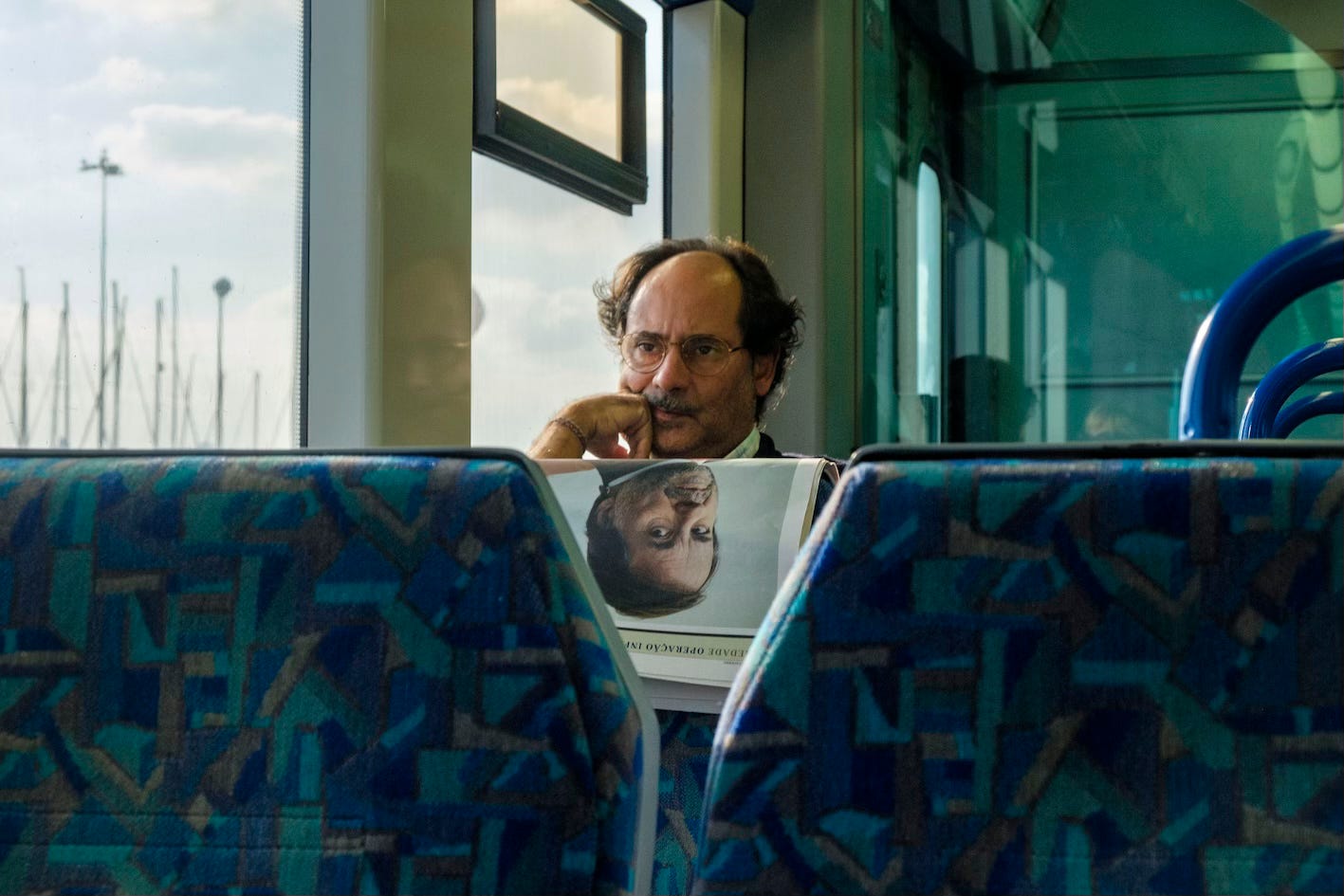 © Gil Ribeiro — a portrait in a newspaper seems to be the reflection of a lone man in a train