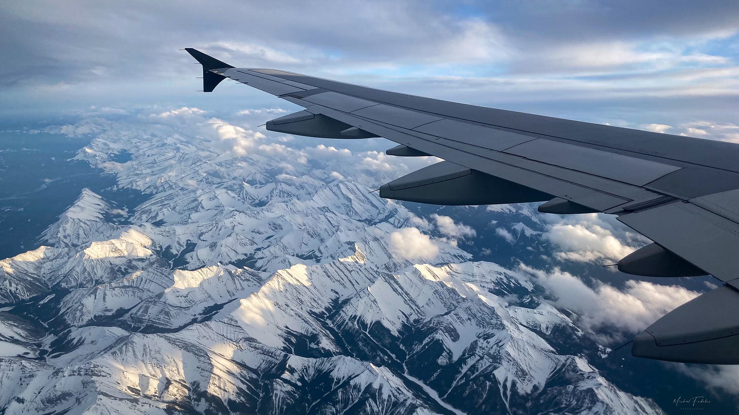 A wing of a plane flying over snow-covered mountains, viewed through a plane window. A wing of a plane flying over snow-covered mountains, viewed through a plane window.
