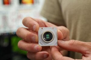 Sharf holds a CMOS-based microelectrode array chip used to precisely locate the electrical activity of single neurons within millimeter-sized organoid tissue.