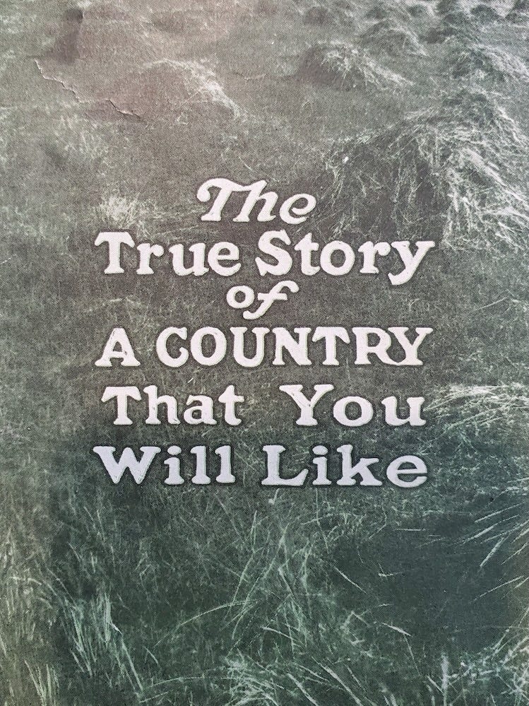 Vintage text reads "The True Story of A Country That You Will Like" against a background of dry grass.