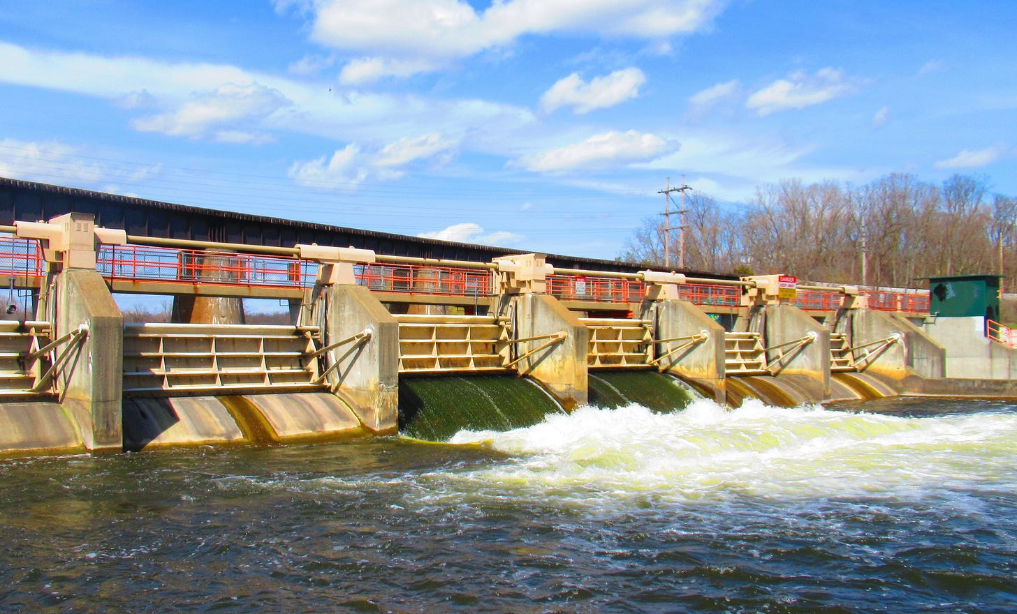 Ann Arbor's Argo Dam, steel and concrete, under a blue sky with white cirrus clouds, and dark waters of the Huron River. Ann Arbor's Argo Dam, steel and concrete, under a blue sky with white cirrus clouds, and dark waters of the Huron River.