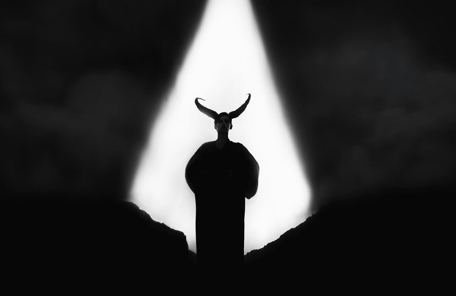 A horned man stands silhouetted in the dark.