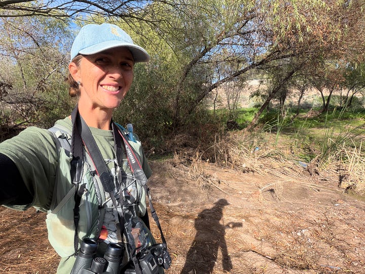 Emily and her mom holding cameras and binoculars while in the wild, both wearing Emily's brain bird t-shirt