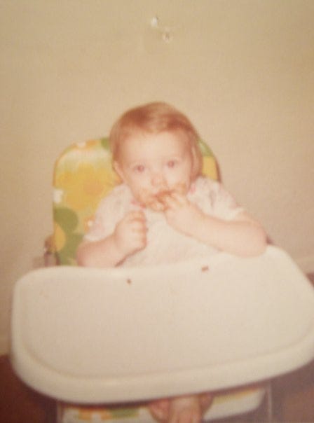 A very adorable baby eats in his high chair.