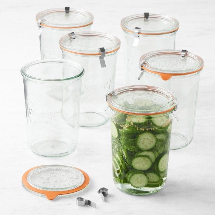 This may contain: several jars with cucumbers in them sitting on a table next to measuring spoons This may contain: several jars with cucumbers in them sitting on a table next to measuring spoons