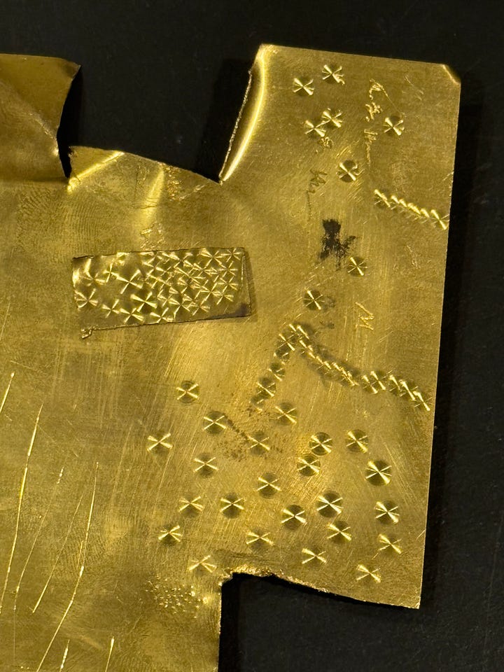 A photograph of amateur perlage work on brass sheet metal, as performed with a simple drill press and Cratex setup.