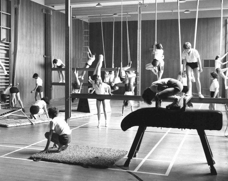 This may contain: an old black and white photo of people in a gym doing exercises on the swings