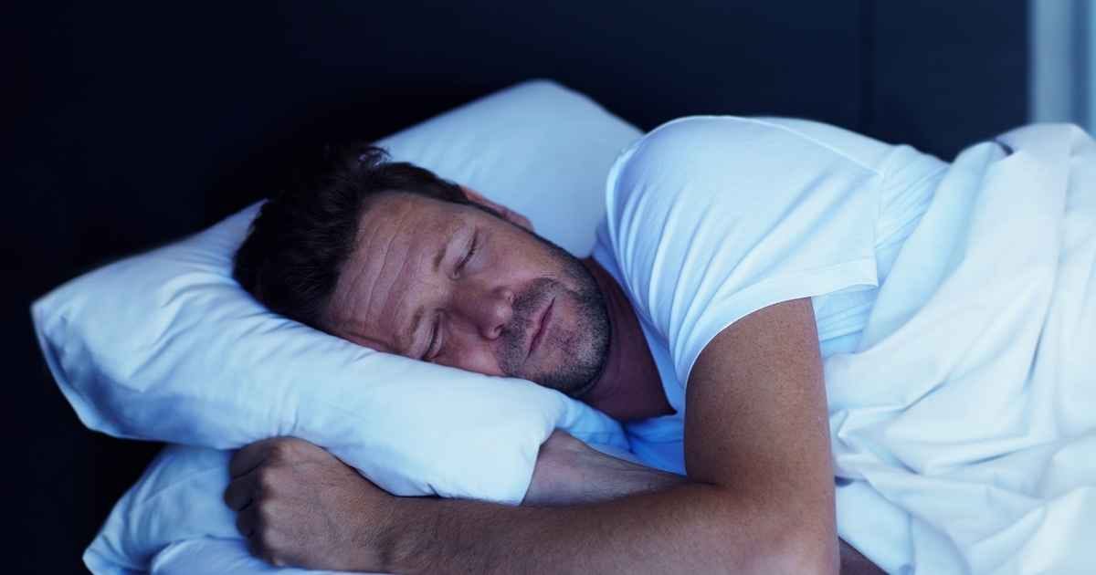man asleep in his bed at home
