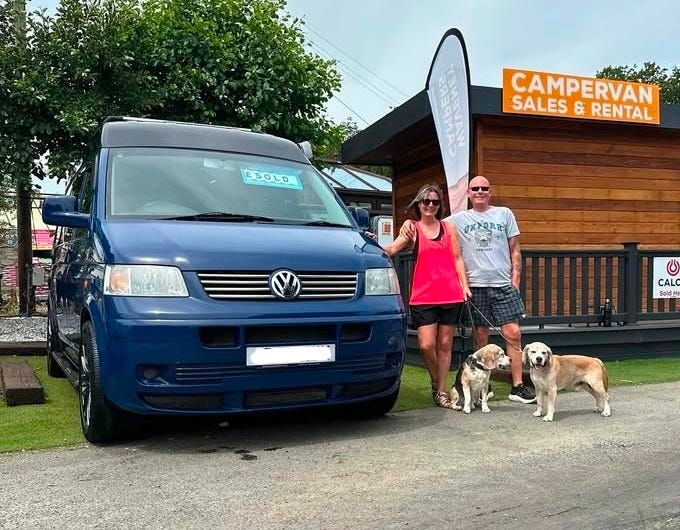 couple with their two beagles picking up a blue vw campervan
