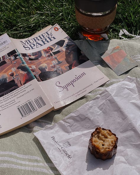 Gallery (3 images) - Image 1: Picnic setup with an open copy of Symposium, coffee in a reusable mug, and a half-eaten canelé. Image 2: Sunlit building front with greenery and a pale blue door. Image 3: My window with a cactus blooming with small pink flowers.
