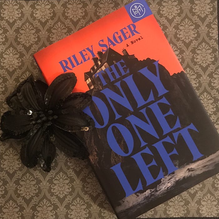 Staged photo of book with black flower and vintage looking background.