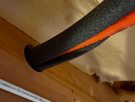 Three photos of a basement renovation in progress. The first shows plumbing pipes set in fresh concrete, the second shows an insulated orange pipe, and the third shows a framed wall with insulation and electrical wiring installed.