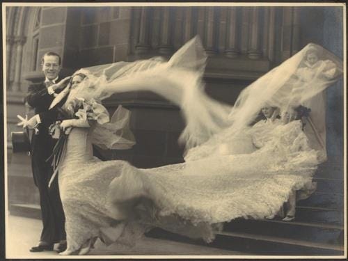 This may contain: a bride and groom are posing on the steps with their wedding dress blowing in the wind