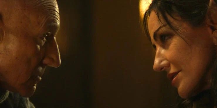 This image shows a two-shot of Jean-Luc Picard (played by Patrick Stewart, on the left) and Laris (played by Orla Brady, on the right), the Romulan supervisor of Château Picard's vineyards, as they lean close to one another during a quiet, intimate conversation. This image shows a two-shot of Jean-Luc Picard (played by Patrick Stewart, on the left) and Laris (played by Orla Brady, on the right), the Romulan supervisor of Château Picard's vineyards, as they lean close to one another during a quiet, intimate conversation.