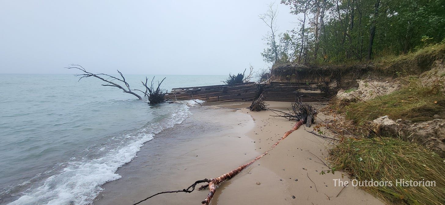 A wooden structure laying on a shallow beach, stretching out into Lake Superior with a foggy horizon in the background.
