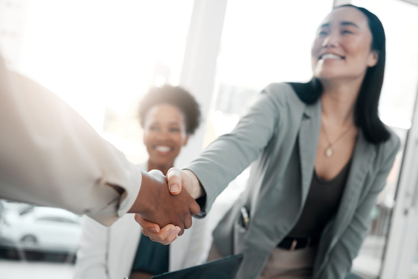 Smiling job candidate shakes hands with interviewer.
