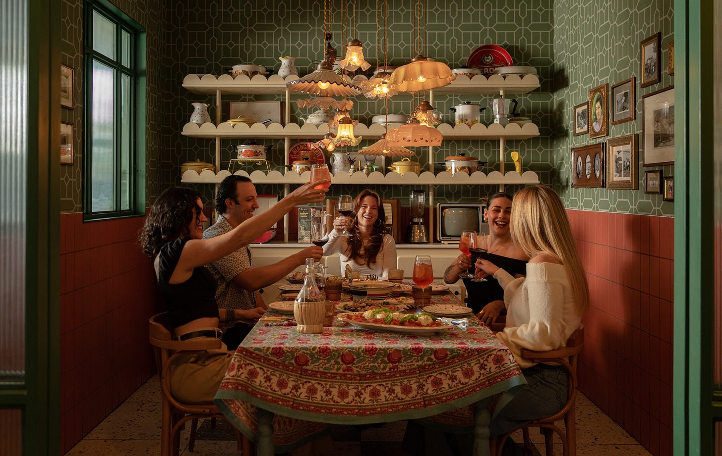 a group gathered around a retro 1970s Italian dinner table raising their glassed for a toast