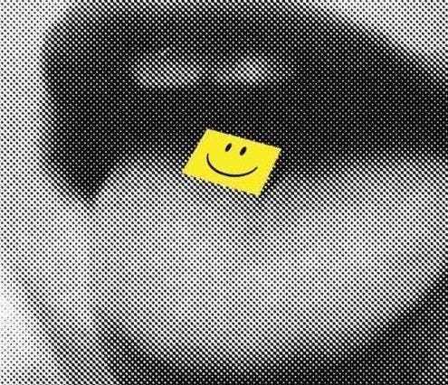 This may contain: a yellow smiley face sticker sticking out of the side of a black and white bag