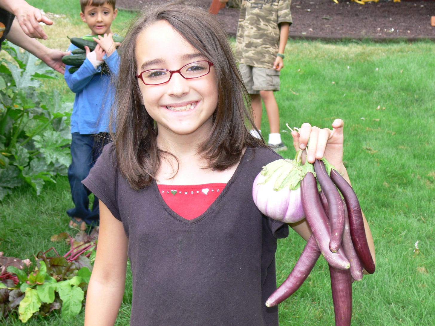 a girl with eggplants and a boy with cucumbers from the garden