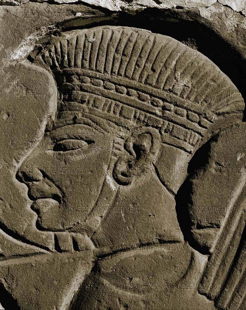 Ancient stone relief showing a detailed profile of a male figure with an elaborately carved headpiece, representing Philistine art and culture