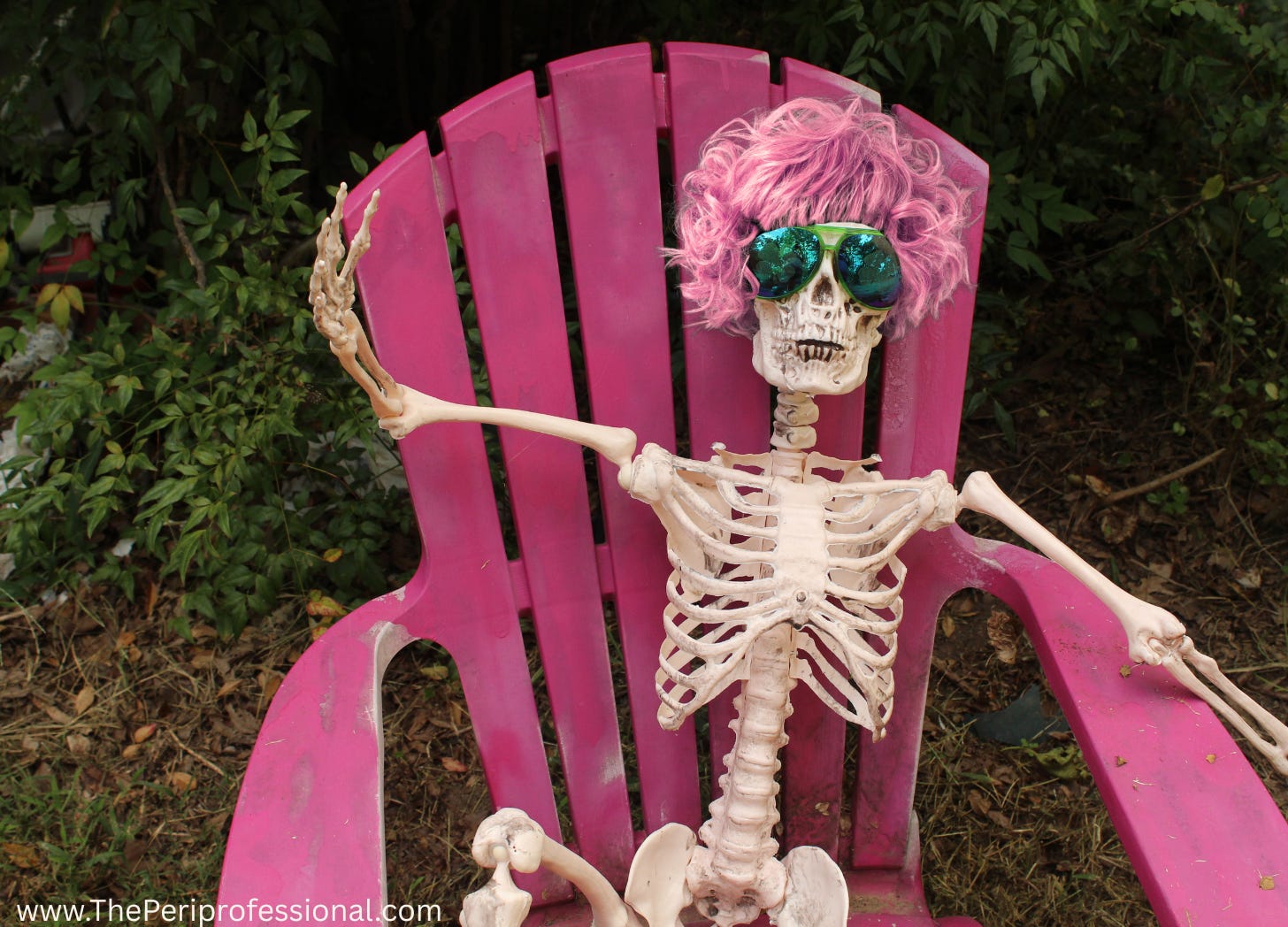 A skeleton with pink hair sitting in a pink chair while wearing sunglasses.