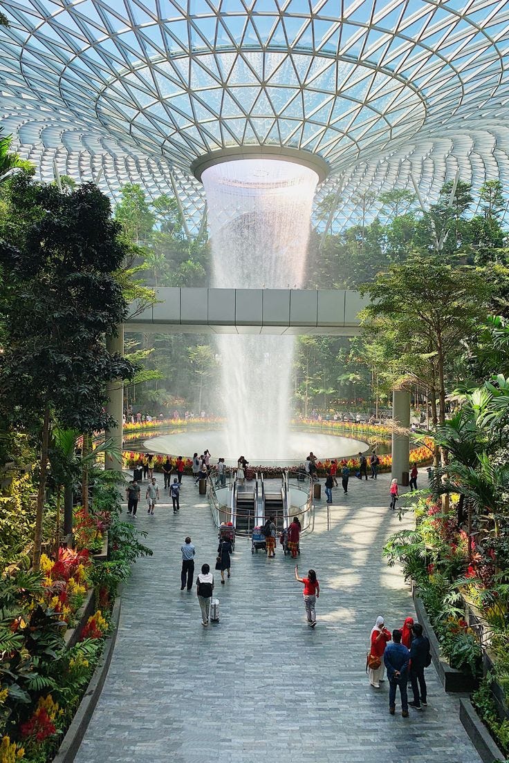This may contain: people are walking around in the middle of an indoor garden with a waterfall coming out of it