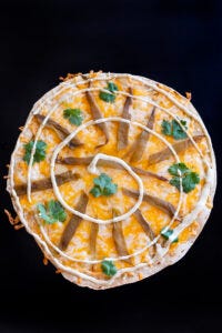 recipe for Arizona style Southwestern flour tortilla cheese crisp with Mexican blend cheese roasted green chile strip, cilantro leaves and ranch spiral.