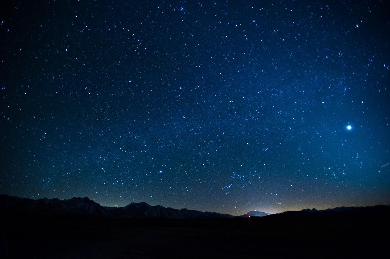 A starry sky over a mountain range

Description automatically generated