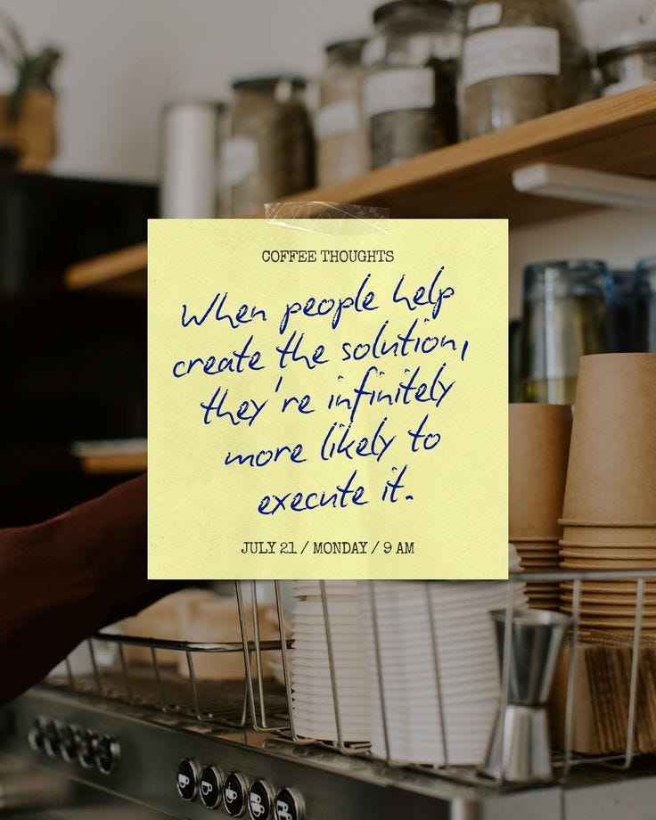 This may contain: a person holding up a yellow sign with writing on it in front of some cups This may contain: a person holding up a yellow sign with writing on it in front of some cups