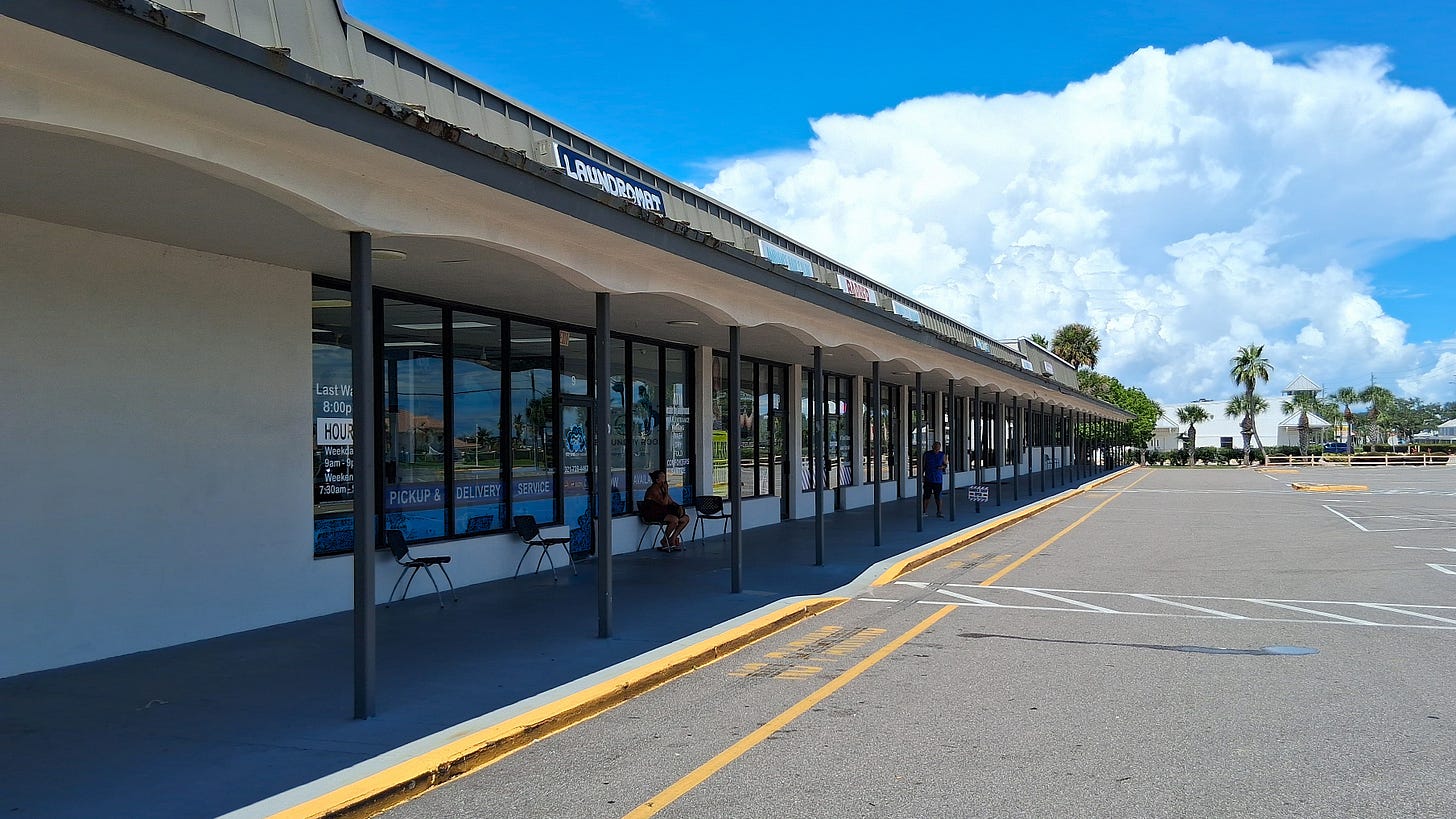 A contrast in eras: the quiet, low-slung commercial spaces that have defined this corner of Palm Bay for decades.