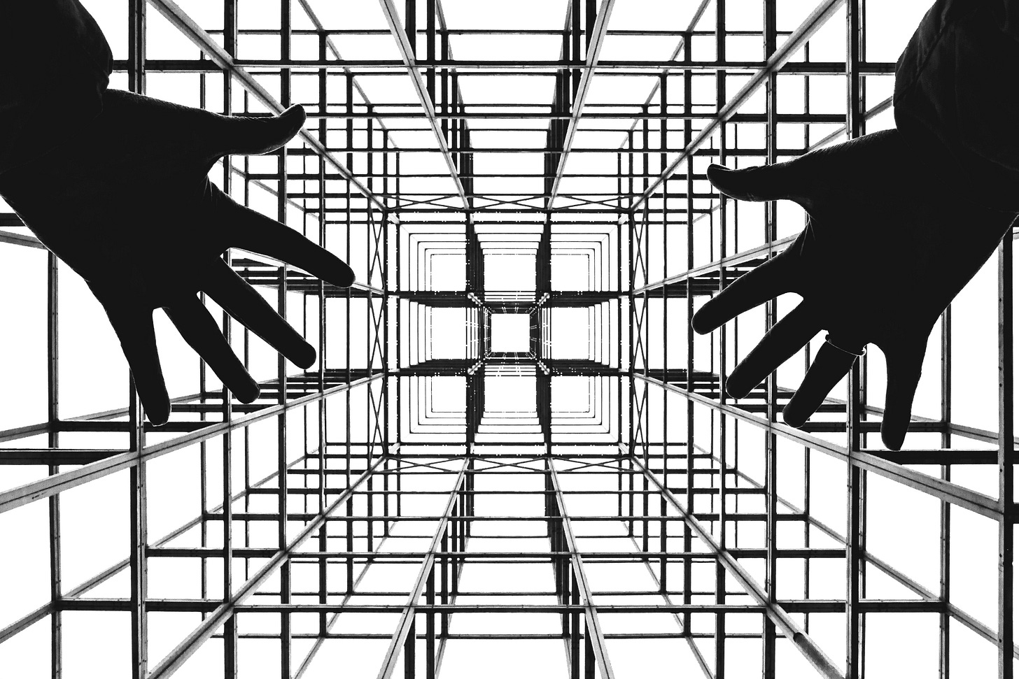 Hands reaching into a rigid geometric grid structure, symbolizing hidden constraints