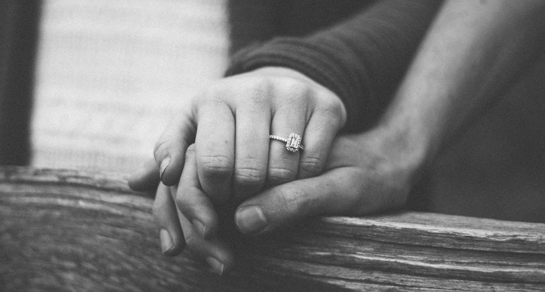 a couple holding hands with a wedding ring visible a couple holding hands with a wedding ring visible