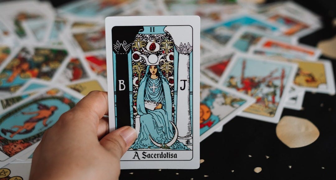 Hand holding a tarot card over a spread.