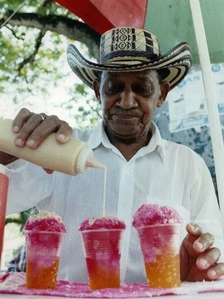 This may contain: a man pouring drinks into cups with straws