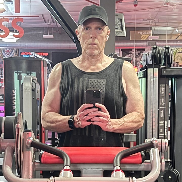 1. Muscular man in gray tank top with grayscale American flag and wearing a black Under Armour ballcap. Holding camera, standing at red-padded gym curling station. 2. Image from smart scale companion app, showing body fat and weight, 200.1 lbs.