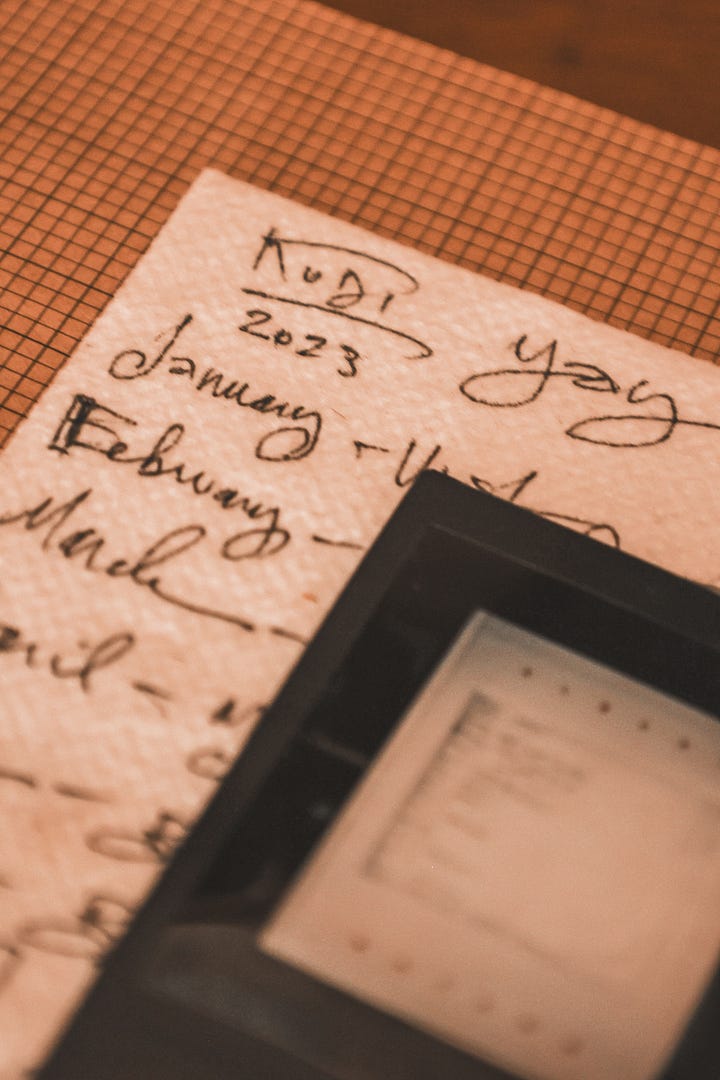 a polaroid of a manifestation napkin sits on top of said napkin inside a journal with graph paper. a fine art print of the stratosphere from downtown las vegas.
