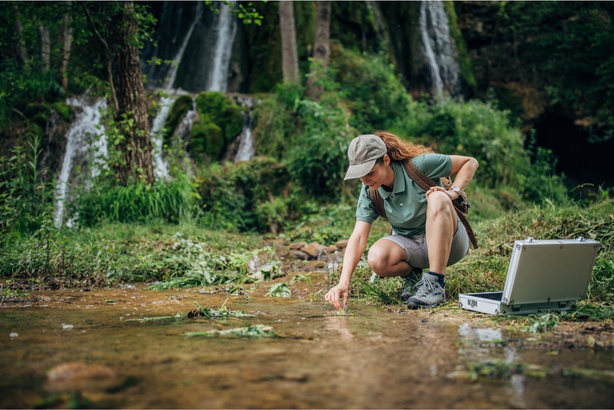 Woman in rainforest taking water sample Woman in rainforest taking water sample