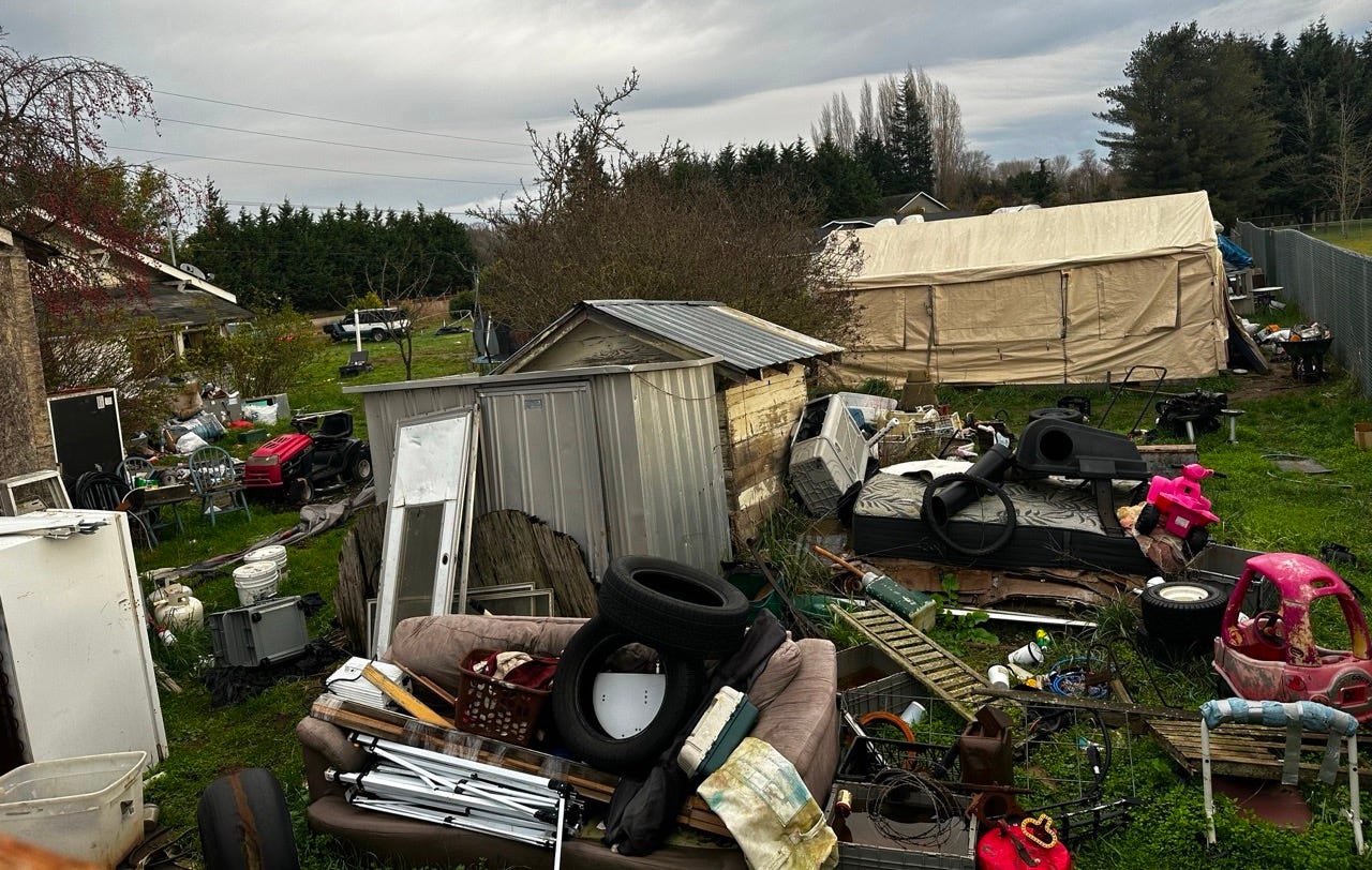 A pile of junk in a yard

Description automatically generated